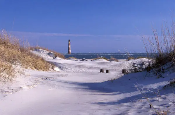 Sandy path with Morris Island lighthouse and ocean in the background